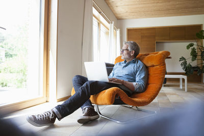 Mature man using laptop in armchair
