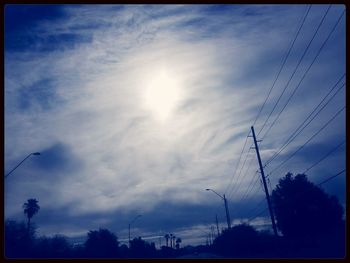 Low angle view of power lines against cloudy sky