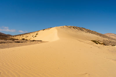 Scenic view of desert against clear blue sky