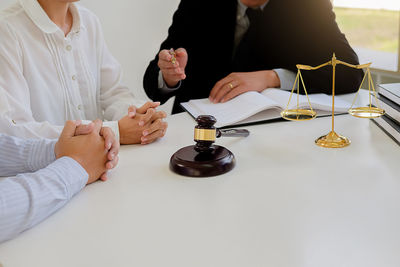 Midsection of lawyer sitting with man and woman