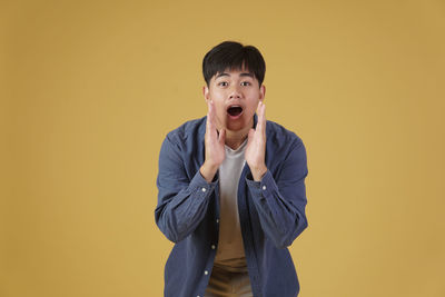 Portrait of smiling man against yellow background