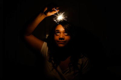 Girl holding lit sparkler in night