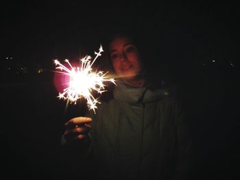 View of woman with fire crackers at night