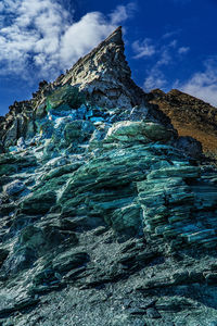 Low angle view of rocks in sea against sky and clouds