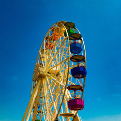 Low angle view of ferris wheel against clear blue sky