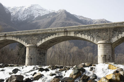 Arch bridge over snowcapped mountains against sky