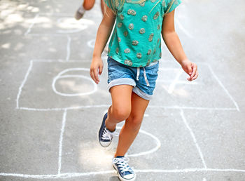 Low section of girl playing hopscotch
