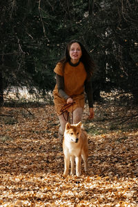 Dog walking in fall forest. beautiful woman with red backpack walking in autumn forest