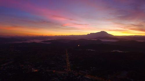 Scenic view of silhouette mountains against orange sky