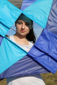 Portrait of young woman looking through kite