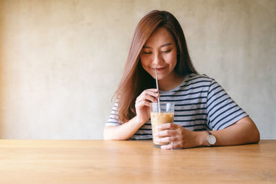 Portrait of young woman drinking glass on table