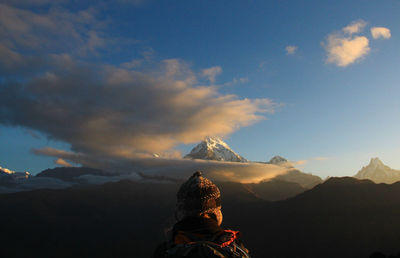 Rear view of person on snowcapped mountain against sky during sunset