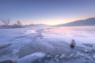 Scenic view of frozen lake against sky during sunset