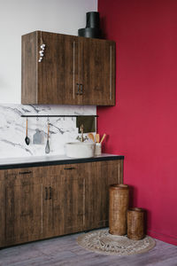 Wooden kitchen against the background of a burgundy wall and marble ceramic tiles