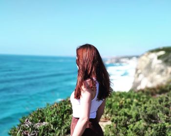 Woman looking at sea shore against sky