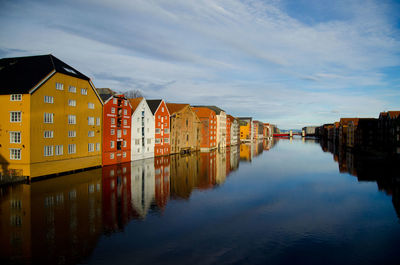 Buildings by river against sky