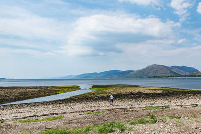 A couple in search of sea treasures at a shore of loch linnhe, scottish highlands, scotland, europe