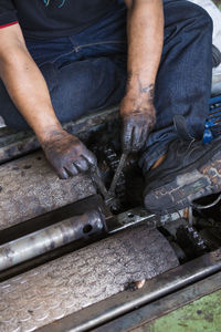 Midsection of man working on machinery in factory