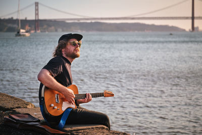 Young man playing guitar at beach