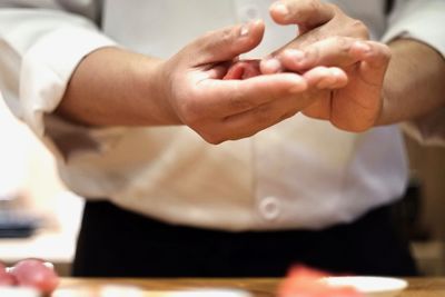 Midsection of woman holding hands in kitchen