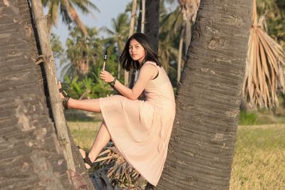 Young woman sitting on tree trunk with saxophone