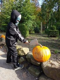 Full length of man with pumpkins against trees during autumn