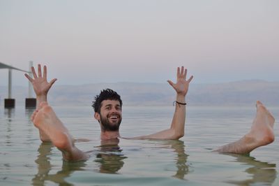 Young man swimming in sea against sky