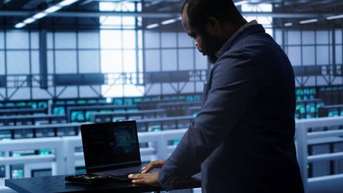 Side view of man using laptop at airport