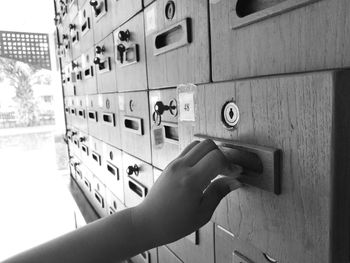 Cropped hand of person opening wooden letterbox