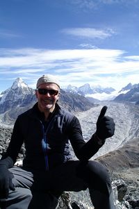 Portrait of man gesturing thumbs up sign while sitting on land