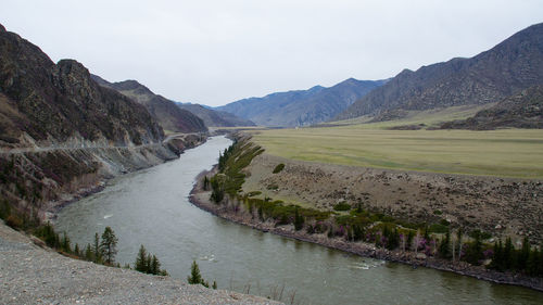 Scenic view of river by mountains against sky