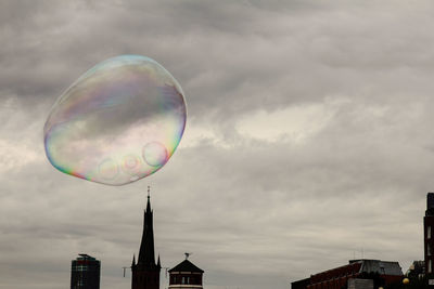 Low angle view of bubbles and building against sky