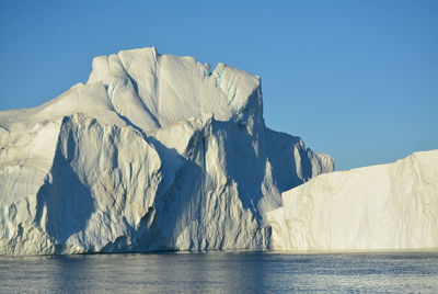 Scenic view of sea against clear sky with beautiful icebergs in the midnight sun ilulissat greenland