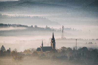 Cathedral against mountains during foggy weather