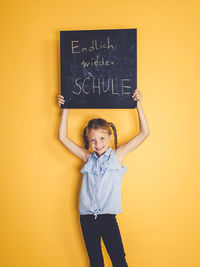 Portrait of boy standing against yellow wall