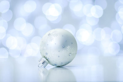 Close-up of christmas bauble on table against illuminated lights