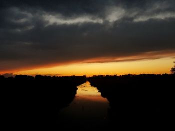 Scenic view of dramatic sky over silhouette landscape during sunset