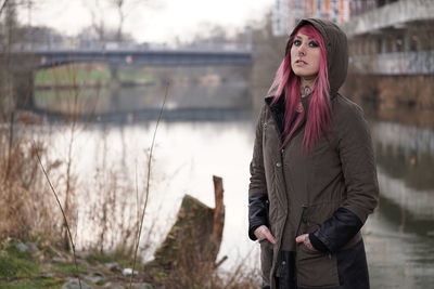 Portrait of confident woman standing against canal