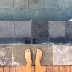 Low section of woman standing by swimming pool