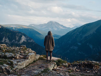 Rear view of man standing on mountain against sky