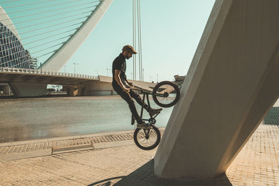 Man riding bmx cycle on footpath in city