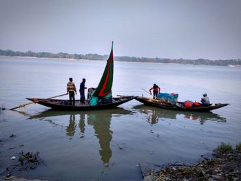 People on boat sailing in sea against sky