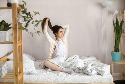 Young woman sitting on bed at home