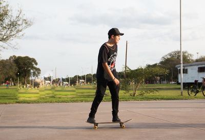 Full length of young man standing on road against sky