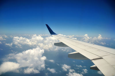 View of airplane wing against cloudy sky