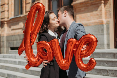 Young couple holding red while standing outdoors