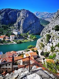 Buildings by river and mountains against clear sky