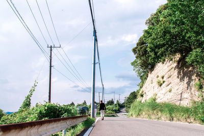 Rear view of man and woman walking on road against sky