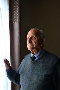 Senior man standing by window at home