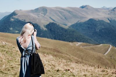 Woman standing on mobile phone in mountains